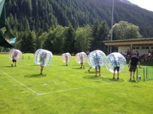 Bubble Soccer auf einen kleinen Feld mit mini Toren. Im Hintergrund sieht man Berge.
